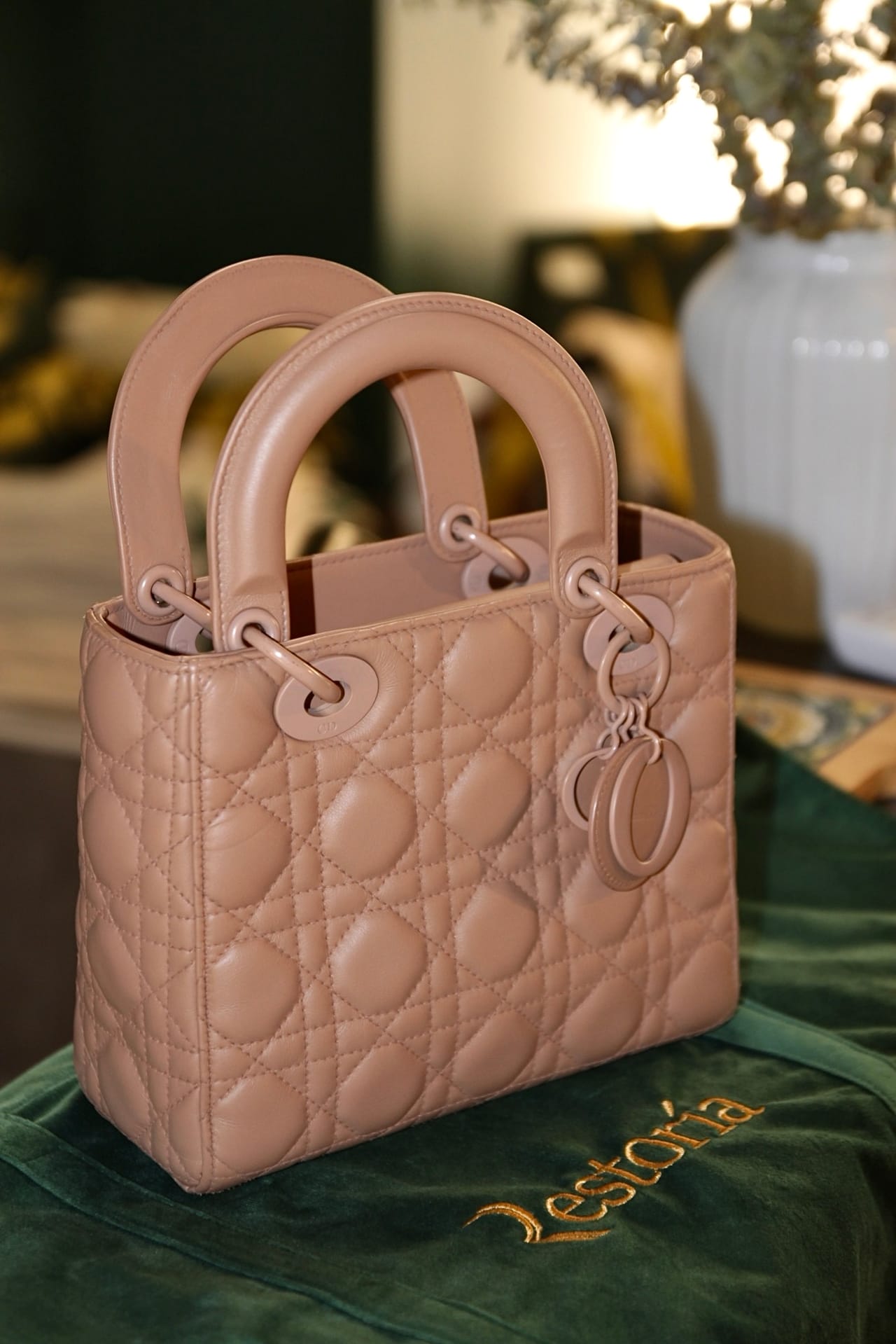 A quilted leather handbag resting on Restoria green velvet, photographed in warm atelier light.
