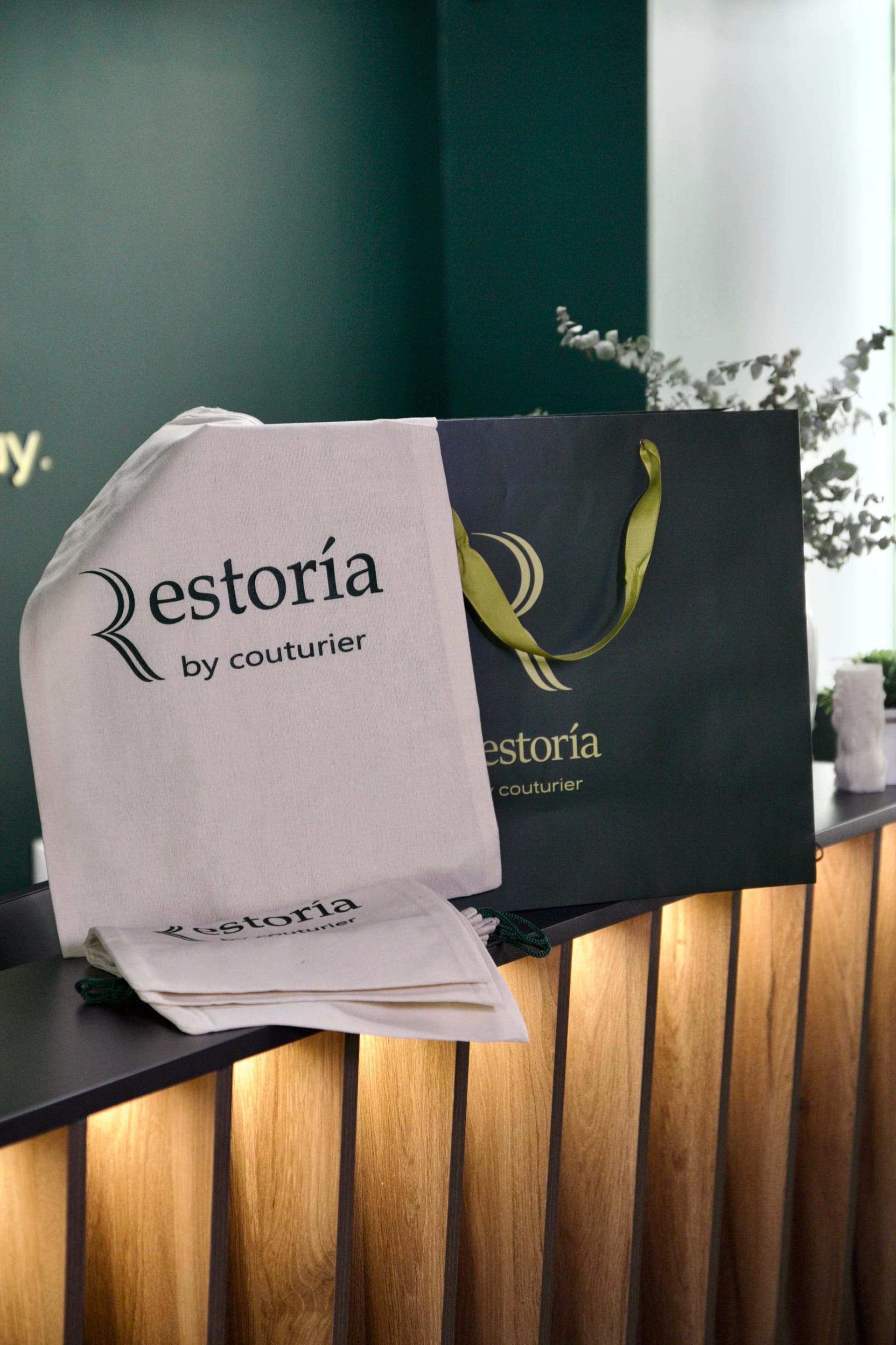 Restoria cotton dust bags and a dark presentation bag on an atelier counter.